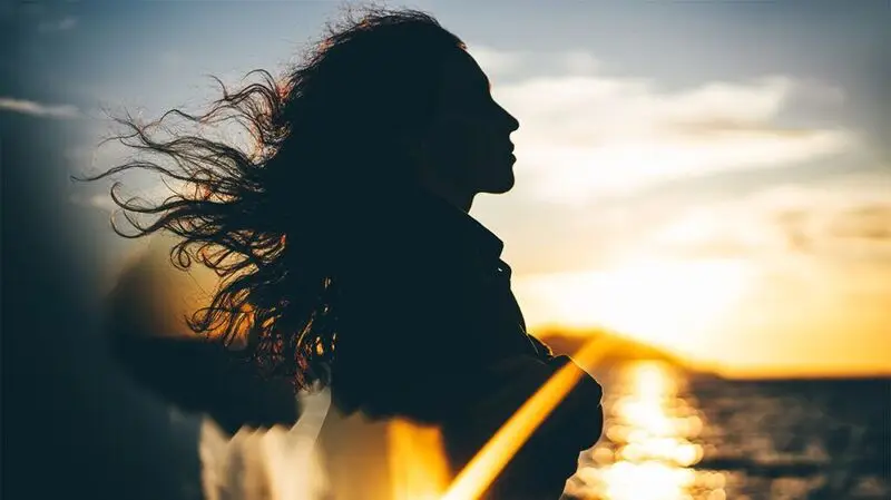 silhouette of woman with long wavy hair blowing in the wind