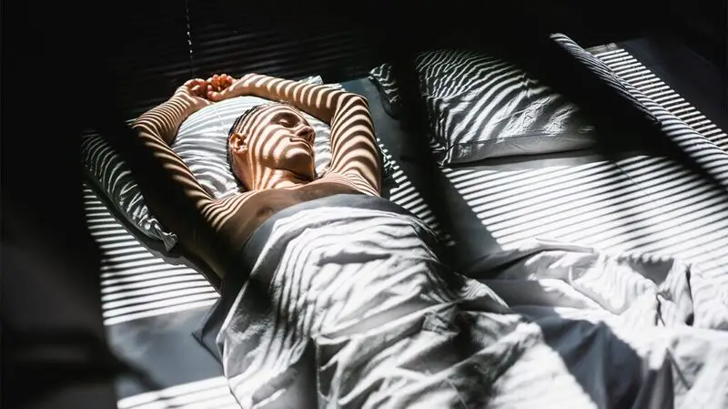 white man asleep on bed with white covers