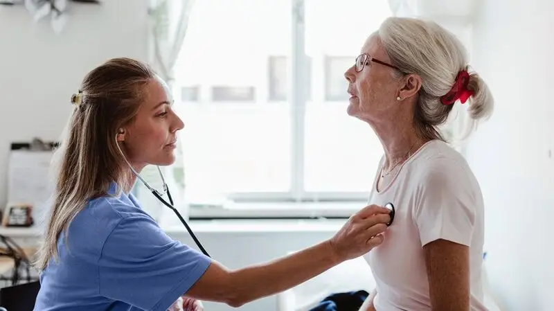 older white woman having her heart checked by younger female doctor with stethoscope