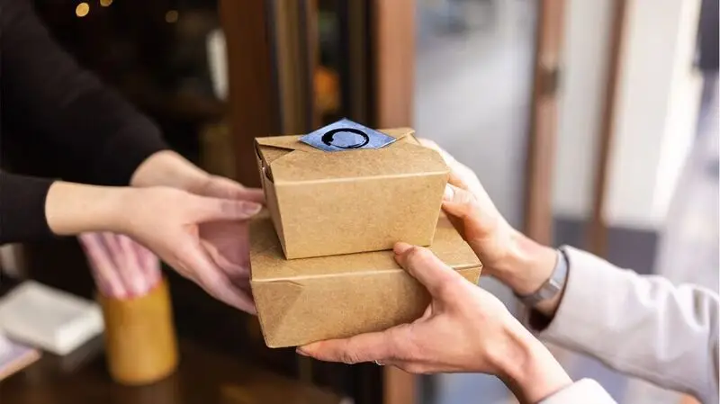 A person collecting their food in takeout boxes.