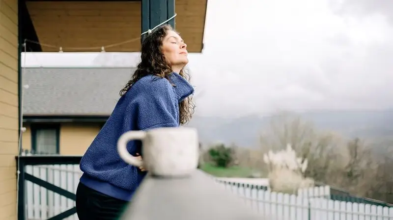 Female on a balcony with a cup of tea looking calm