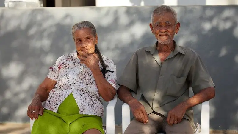 oler man and woman from Brazil sitting on chairs outdoors in the sun