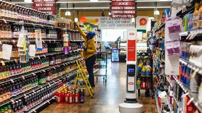 The beverages and drinks aisles in a supermarket as a person reaches for an item on the top shelf