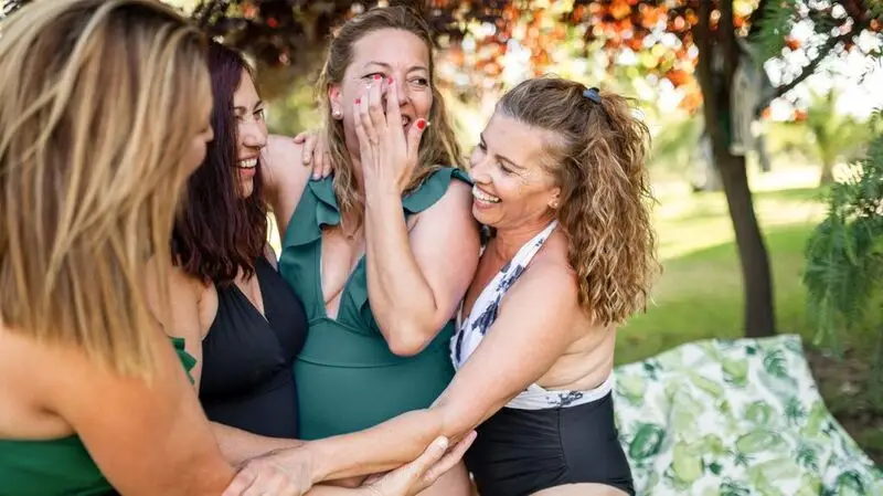 A group of middle-aged women wearing swimsuits and laughing