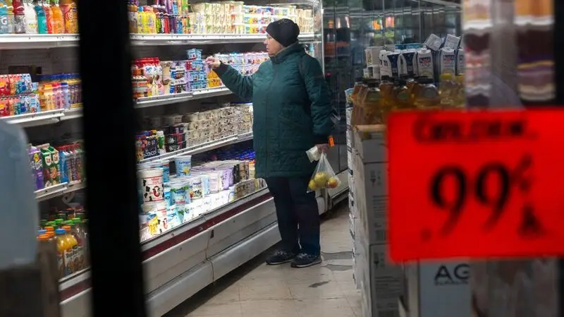 older woman in green jacket browsing supermarket shelves
