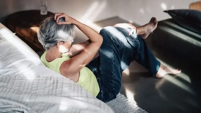 older white woman seen from behind, holding her head