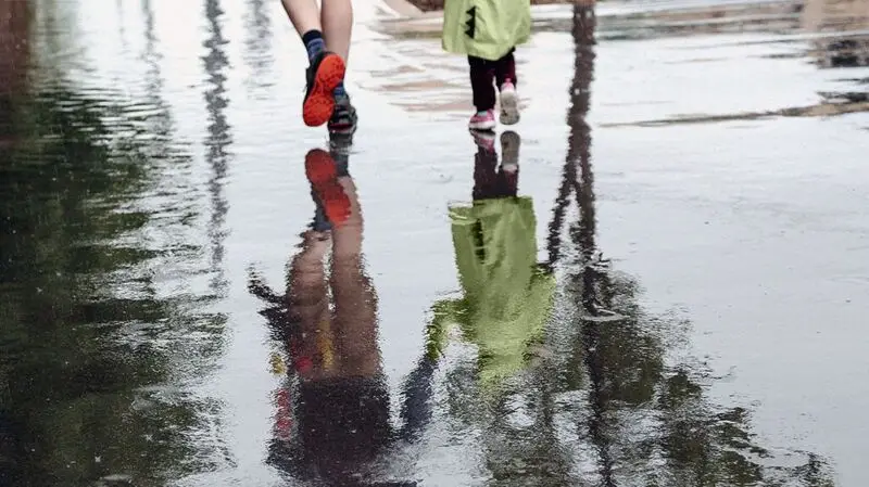 two people's feet walking on wet pavement