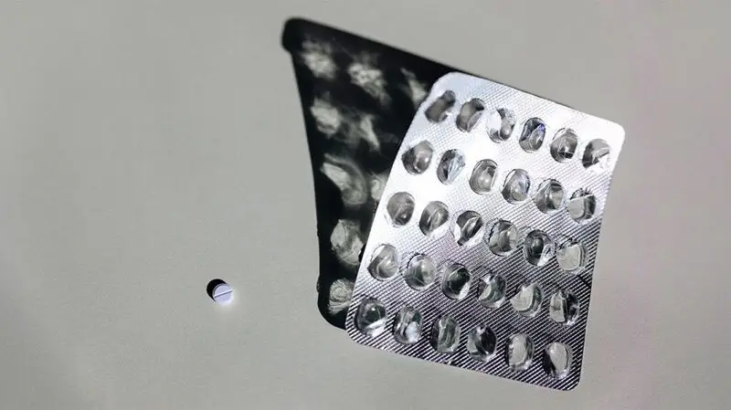 A pill sits next to an empty blister pack of levetiracetam