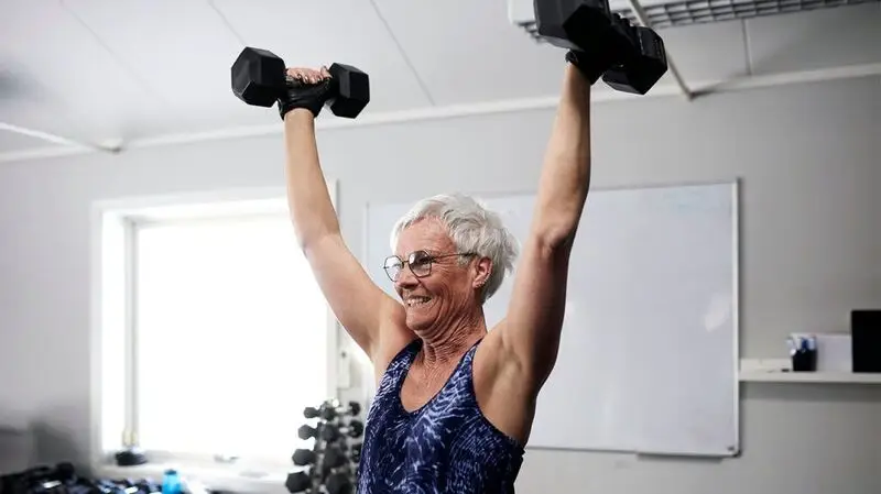 An older female exercising with dumbbells.