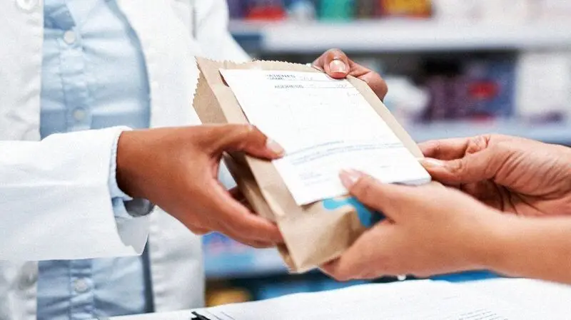 A person receiving their prescription from a pharmacy.