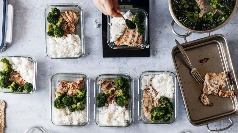 Healthy meal prep recipes featuring the same meal of grilled chicken, broccoli and rice in glass containers on a kitchen counter