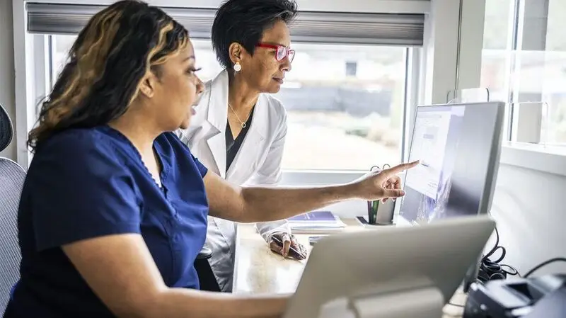 A doctor and nurse conferring at reception desk in doctor's office.