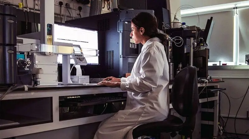 A laboratory worker looking at a screen.