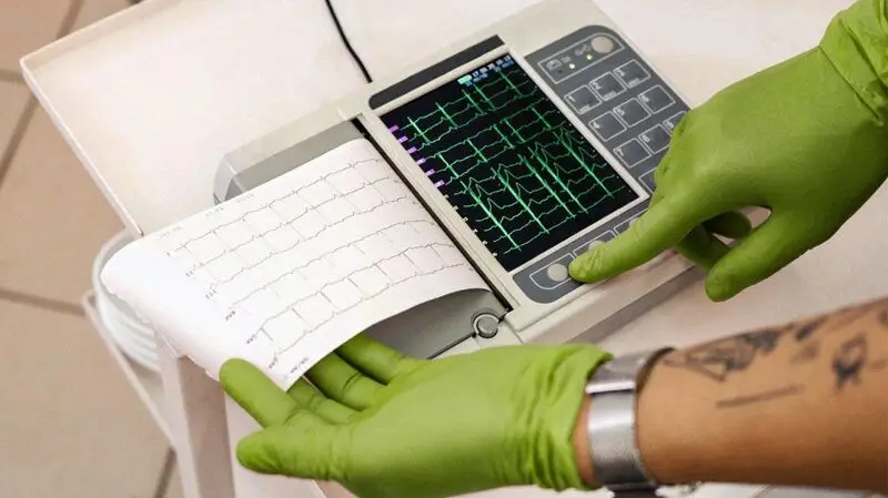 A healthcare professional operating a portable electrocardiogram (ECG) machine.