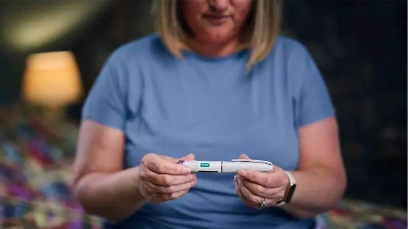 older white woman holding glp-1 injection dose
