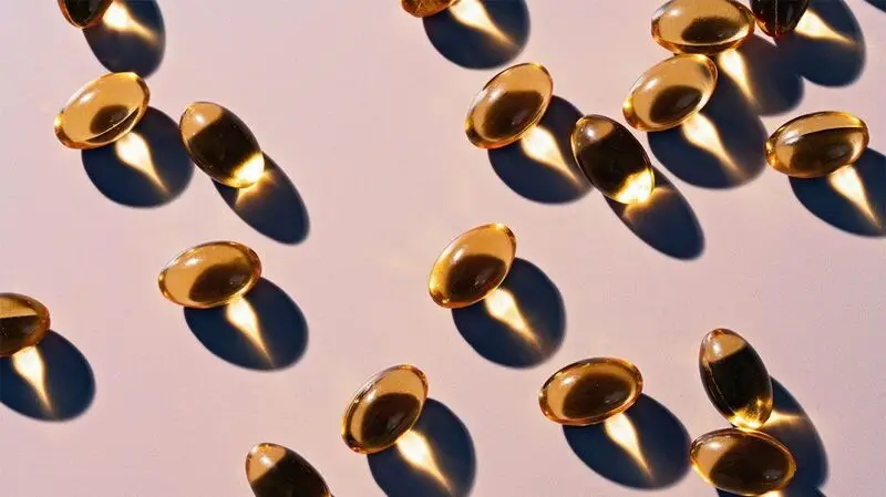 Vitamin D capsules scattered on a flat surface as sunlight creates shadows