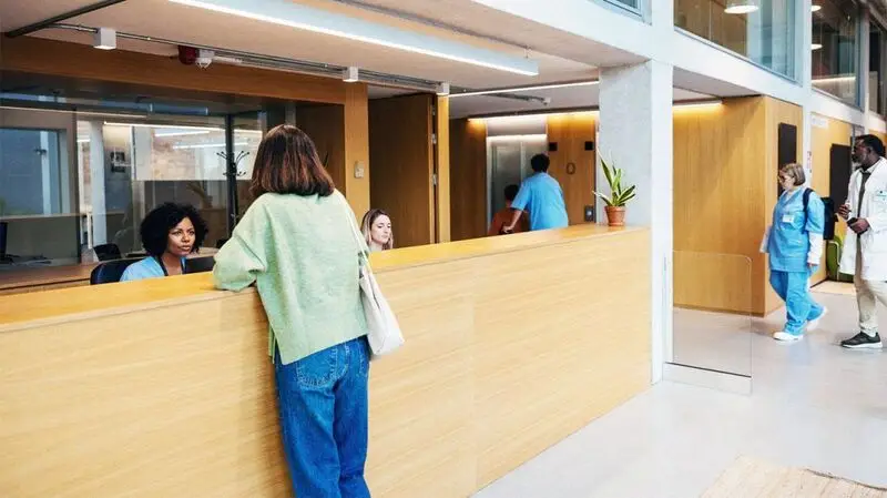 An IBD patient speaks to reception at a hospital facility