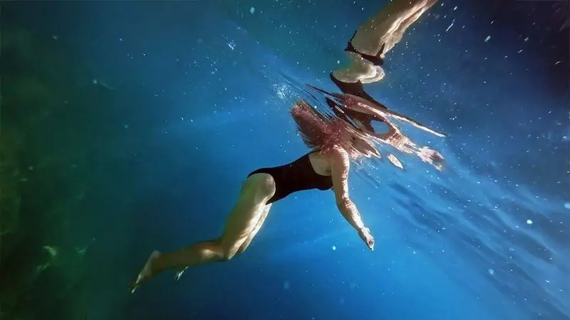 white woman in black one-piece swimsuit swimming