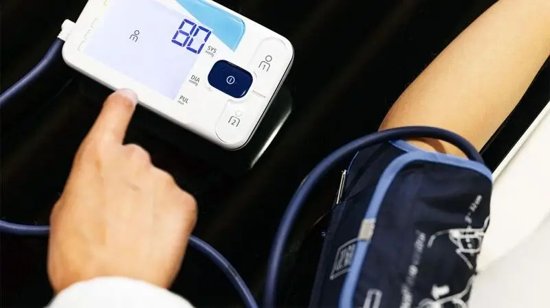 A person using a digital blood pressure monitor.
