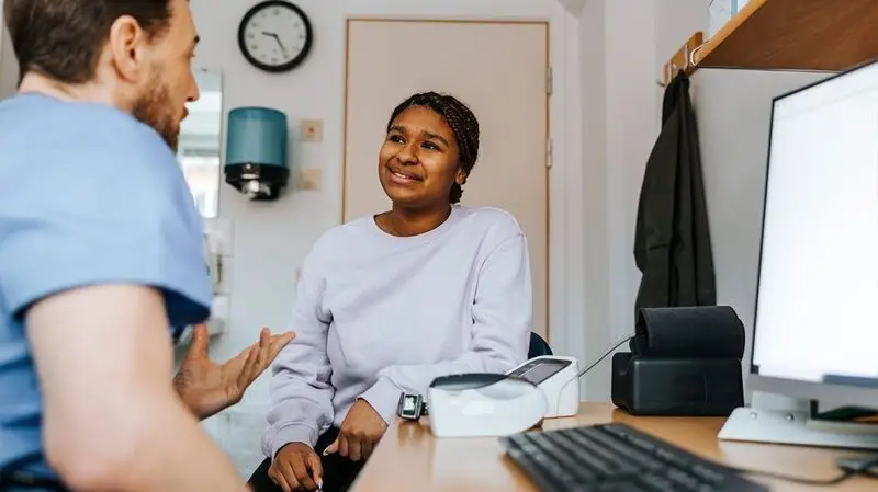 young Black woman speaking to white male ob-gyn