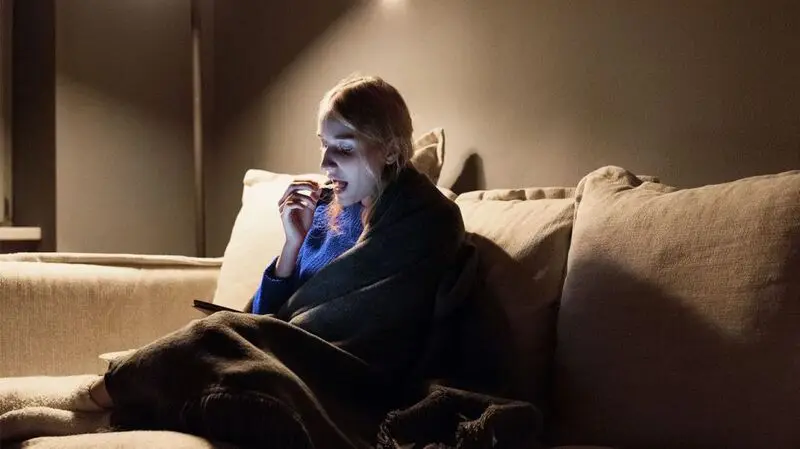A woman eats a snack in bed late at night