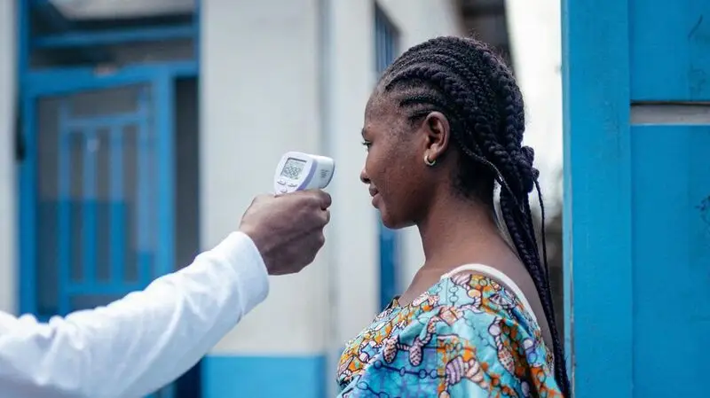 young Black woman being scanned for body temperature