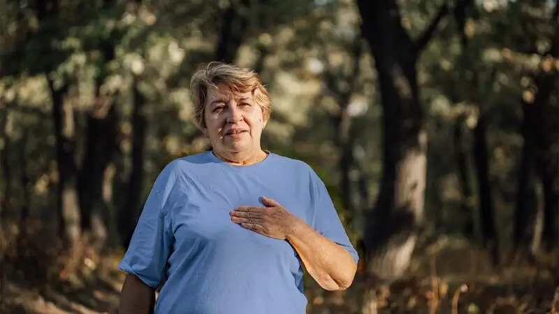 older white woman holding a hand over her heart