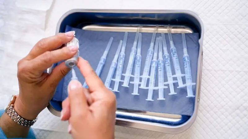 A healthcare professional preparing vaccine syringes.