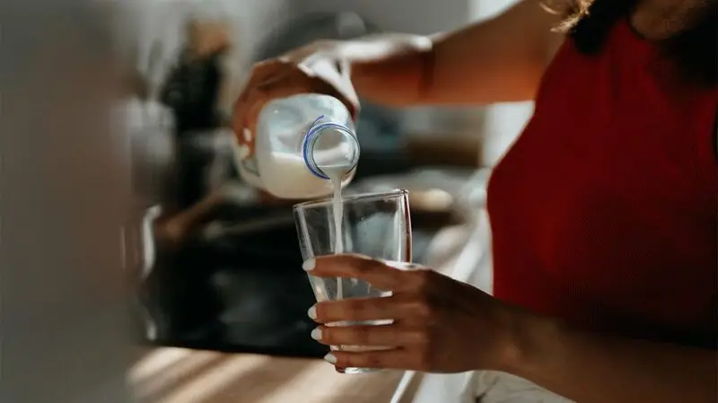 A person pouring a glass of milk.