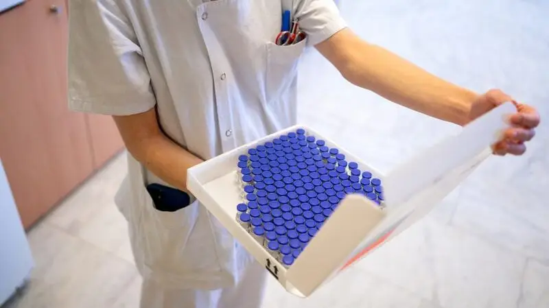 A nurse holds a box full of vaccine vials