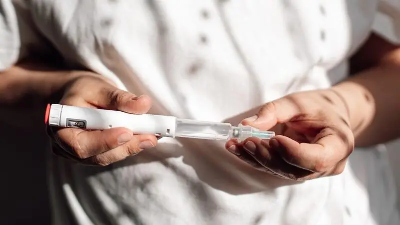 A woman holds an injector for a GLP-1 medication, the most common of which are Ozempic and Wegovy