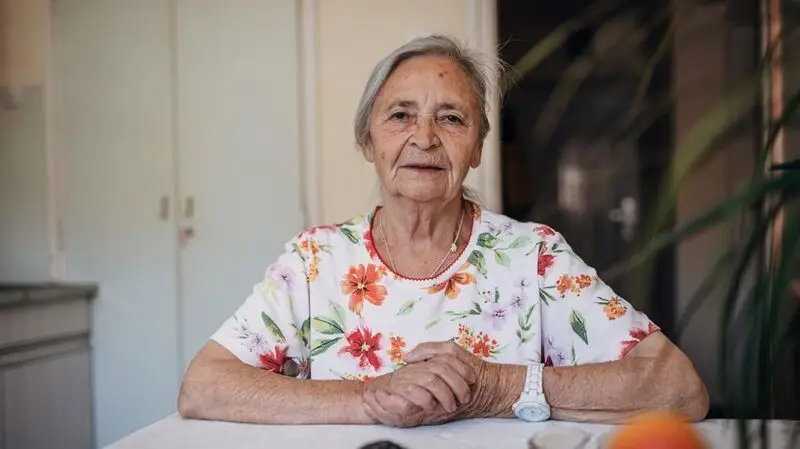 An older adult sitting at a table.
