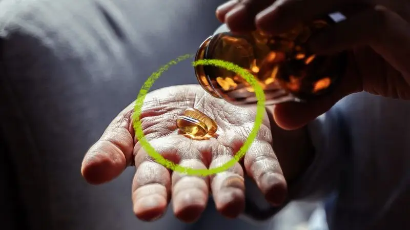 A fish oil capsule in a person's hand.
