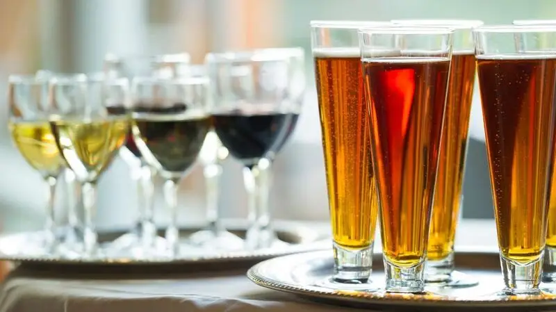 Various wines and beers in glasses on two trays on a table